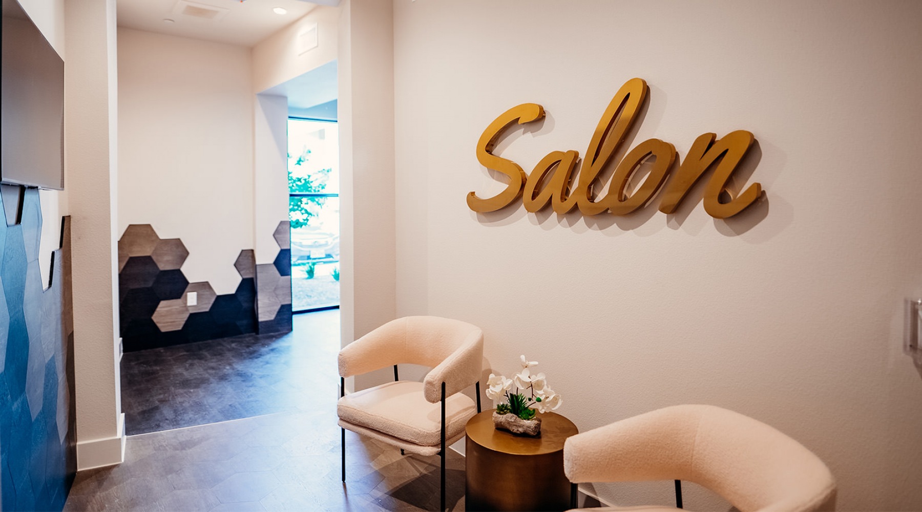 Exterior of the salon at The Hamilton at Garden Valley Apartments in Waxahachie, TX, featuring a sign and chairs.